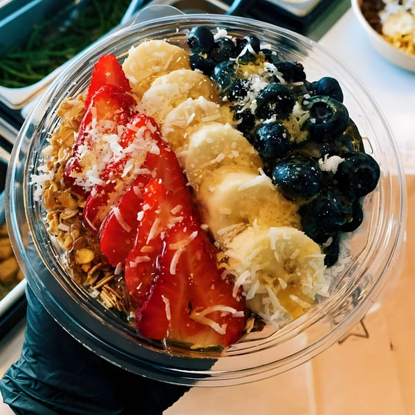 Scooters' healthy fruit bowl with strawberries, bananas, blueberries, granola, and coconut flakes.